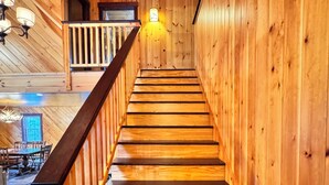 Un escalier en bois avec une rampe, menant à un balcon.