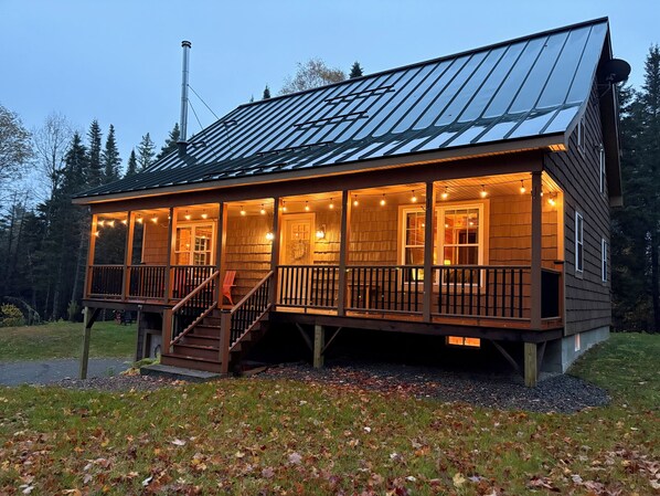 A wooden cabin with a covered porch, a staircase, and a metal roof.