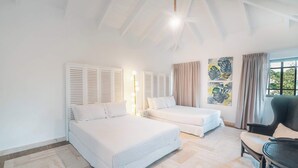Un dormitorio con dos camas, una silla y una ventana con cortinas.