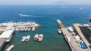 A marina with boats docked, a pier with umbrellas, and a mountain in the background. - Maison Marika in Sorrento (Sorrento)