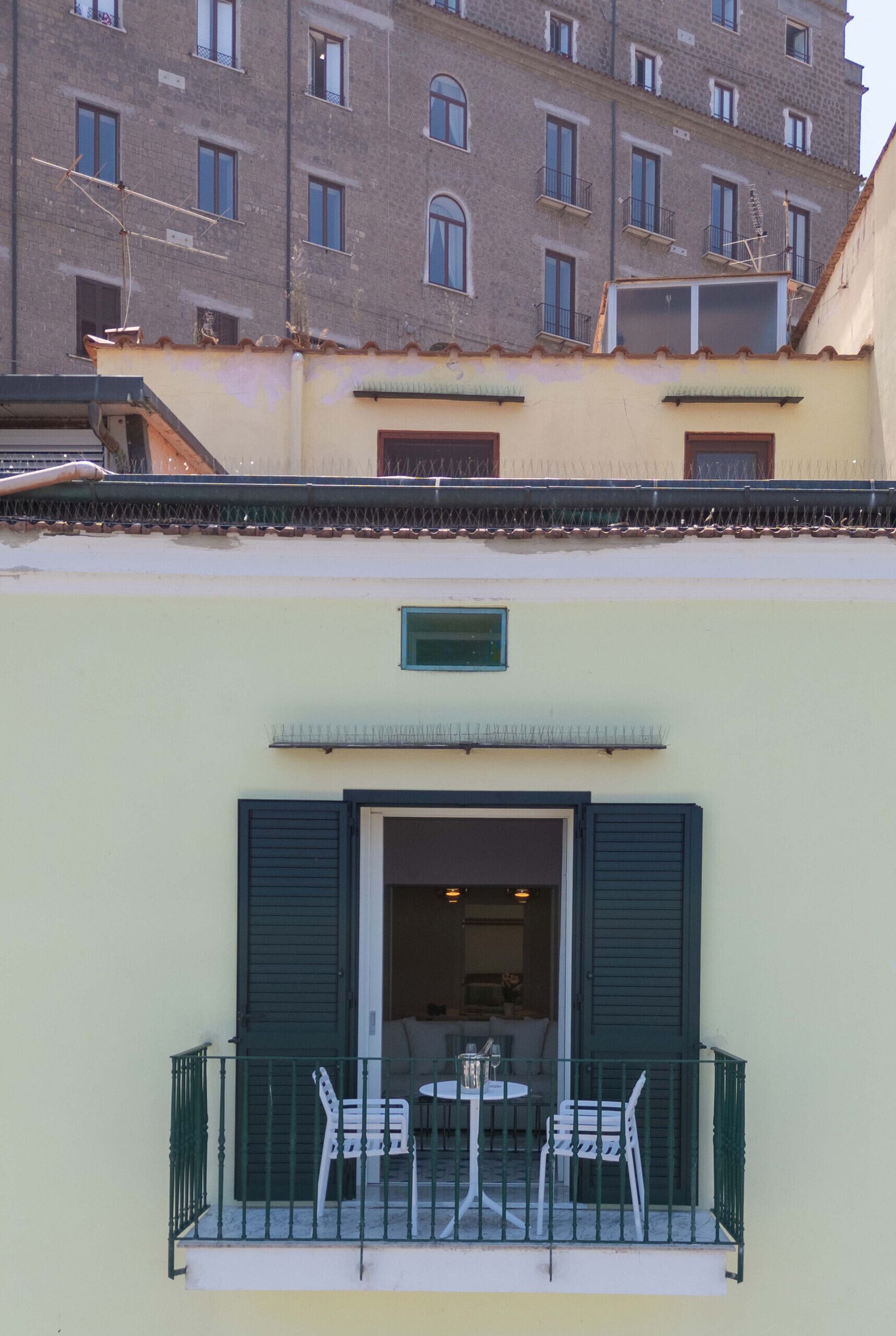 A building with a balcony featuring two white chairs and a table.