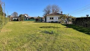A residential property with a well-maintained lawn, a single-story house, and a clear blue sky.