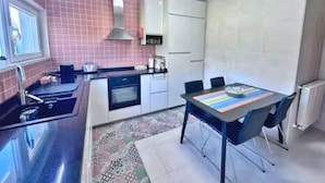 A modern kitchen with a built-in oven, a stainless steel sink, and a dining area with a table and chairs.