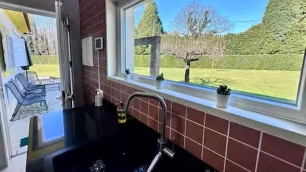 A kitchen with a window view of a garden.