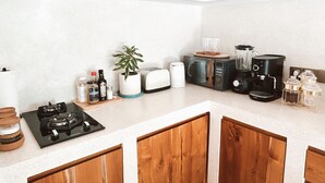 Et køkken med gasblus, brødrister, blender, kaffemaskine og en potteplante.