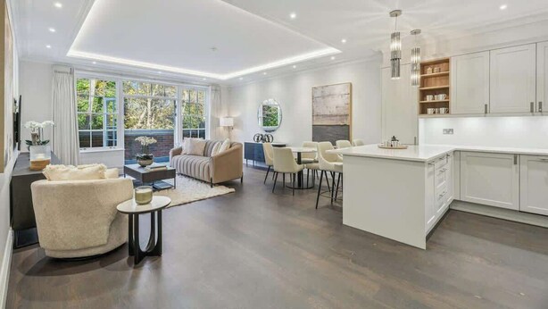 A spacious living area with a large window, a sofa, a dining table, and a kitchen with white cabinets and a central island. - Luxury 2BR|Exclusive Gated Development by Tempstay (Sunningdale)
