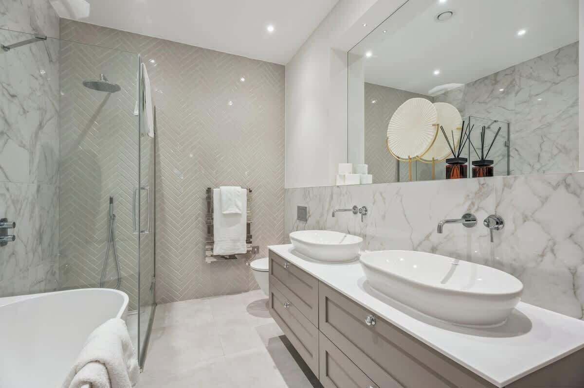 Une salle de bain moderne avec une douche à parois de verre, deux lavabos et un grand miroir.
