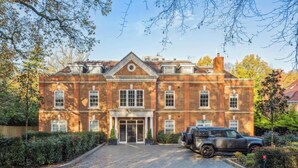A large brick building with a central entrance, a driveway, and a parked SUV. - Luxury 2BR|Exclusive Gated Development by Tempstay (Sunningdale)