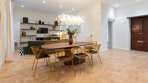 Un comedor con una mesa de madera y sillas amarillas, un jarrón con flores y una lámpara de araña moderna.