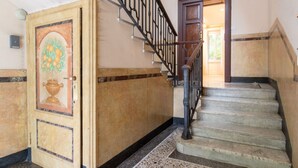 Una escalera con barandilla de metal negro que conduce a una puerta con un panel decorativo.