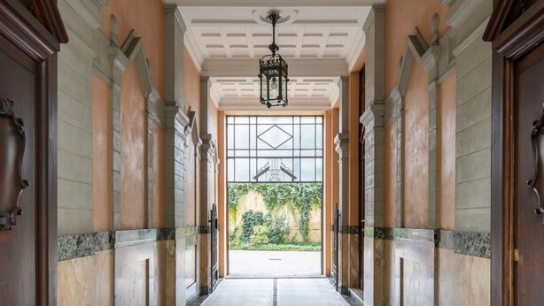 Un pasillo con un amplio arco de entrada que da a un jardín.