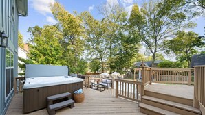 A wooden deck with a hot tub, outdoor furniture, and a wooden fence. - Big Pool, Hot Tub & Gym at Spacious 5 Bedroom Home (Overland Park)