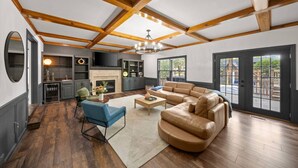 A spacious living room with a large L-shaped sectional sofa, a fireplace, and a dining area with a table and chairs. - Big Pool, Hot Tub & Gym at Spacious 5 Bedroom Home (Overland Park)