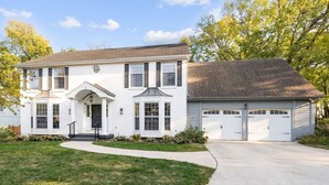 A two-story house with a front porch, a garage, and a well-maintained lawn. - Big Pool, Hot Tub & Gym at Spacious 5 Bedroom Home (Overland Park)