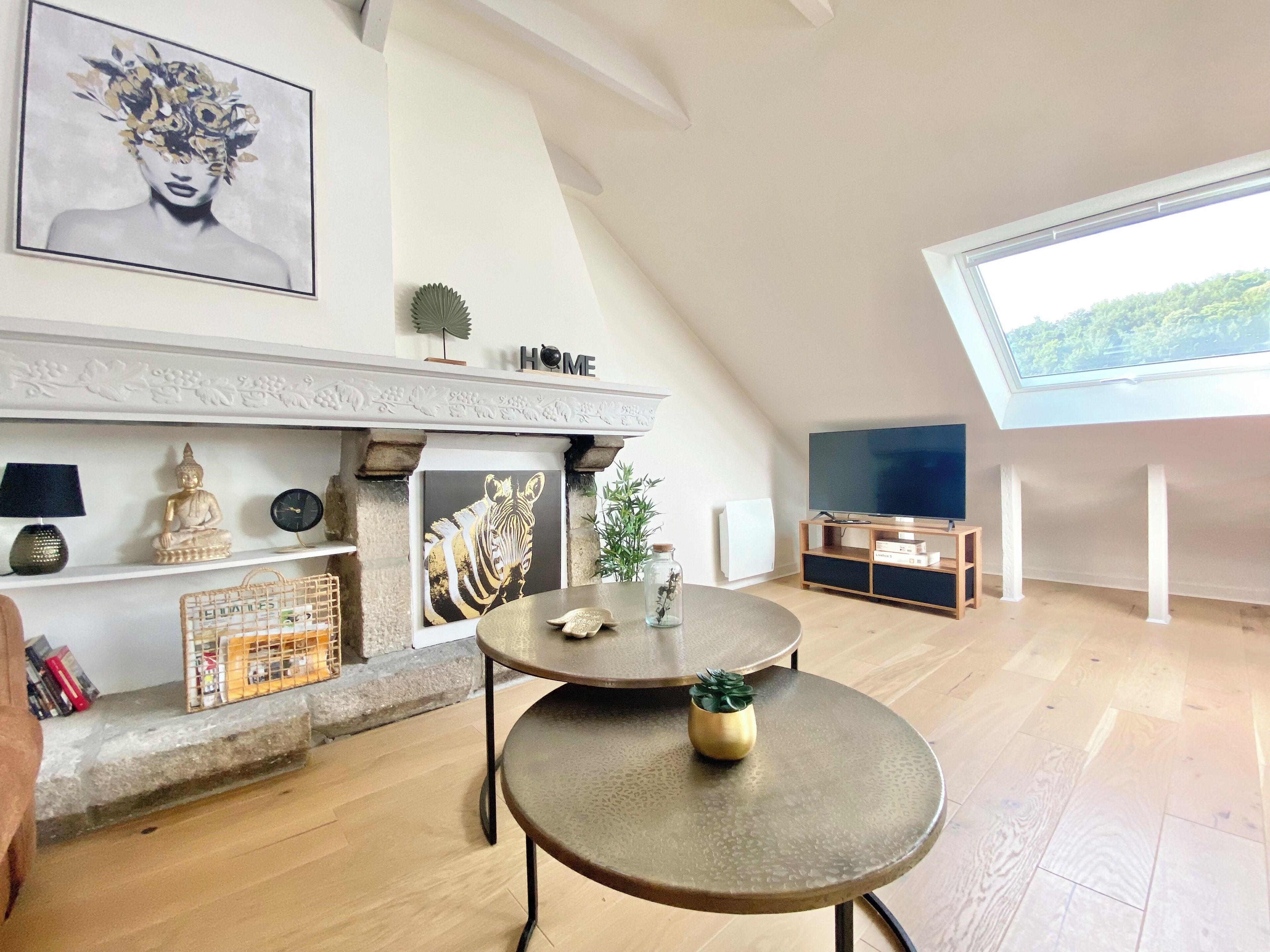 A modern living room with a fireplace, a television, and a skylight.