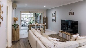 A modern living room with a sofa, TV, and dining area.