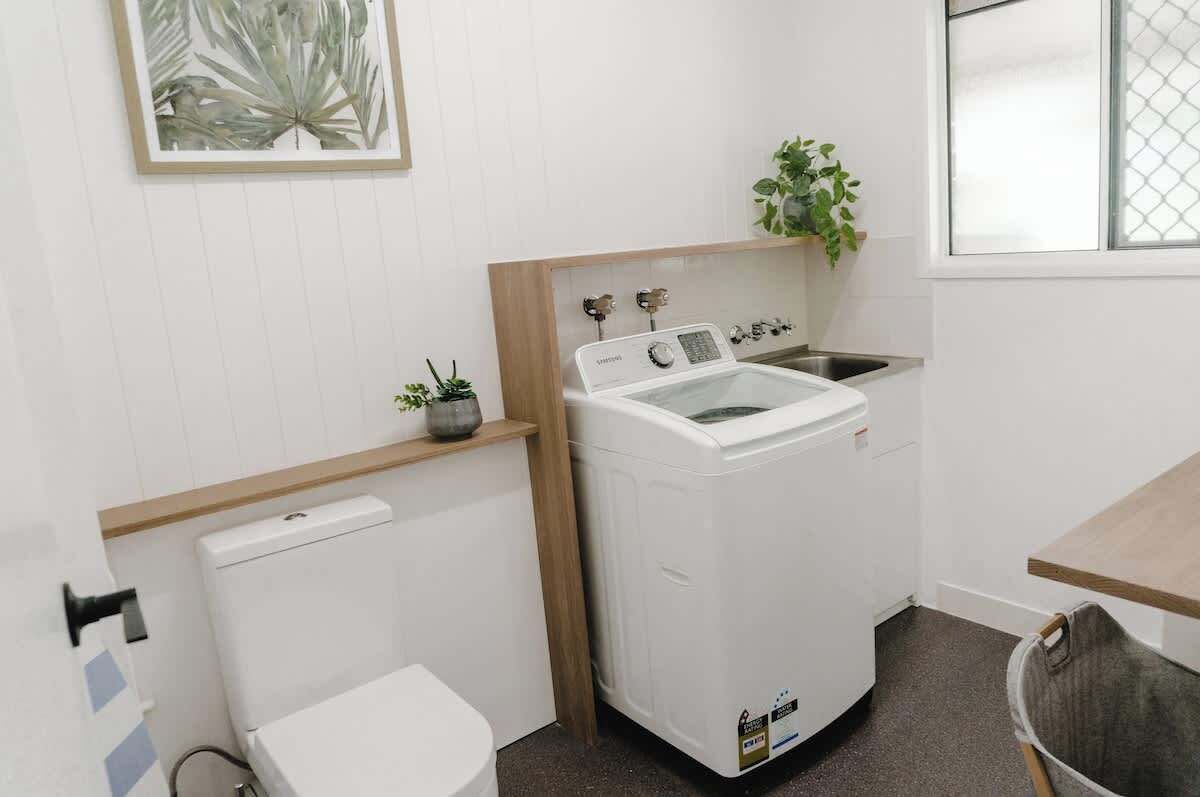 Uma lavanderia compacta com máquina de lavar, pia e vaso sanitário.