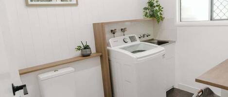 Uma lavanderia compacta com máquina de lavar, pia e vaso sanitário.