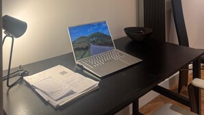 A desk with a laptop, papers, and a framed artwork on the wall. - A brand new apartment decorated to a  high standard in a landmark development. (London)