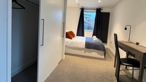 A bedroom with a bed, a desk, and a closet. - A brand new apartment decorated to a  high standard in a landmark development. (London)