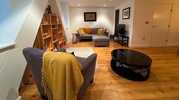 A modern living room with a grey sofa, a coffee table, and a bookshelf. - A brand new apartment decorated to a  high standard in a landmark development. (London)
