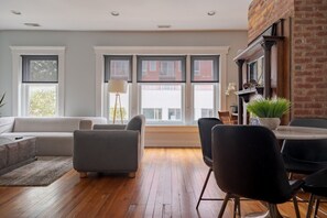Een moderne woonkamer met een bank, stoelen, een eettafel en een open haard.