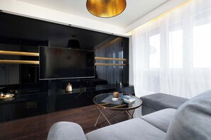 Ein modernes Wohnzimmer mit einem großen Flachbildfernseher, einem runden Couchtisch und einem Sofa.