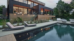 Une maison moderne dotée d’une piscine, d’un espace salon extérieur et d’un escalier menant à une terrasse.