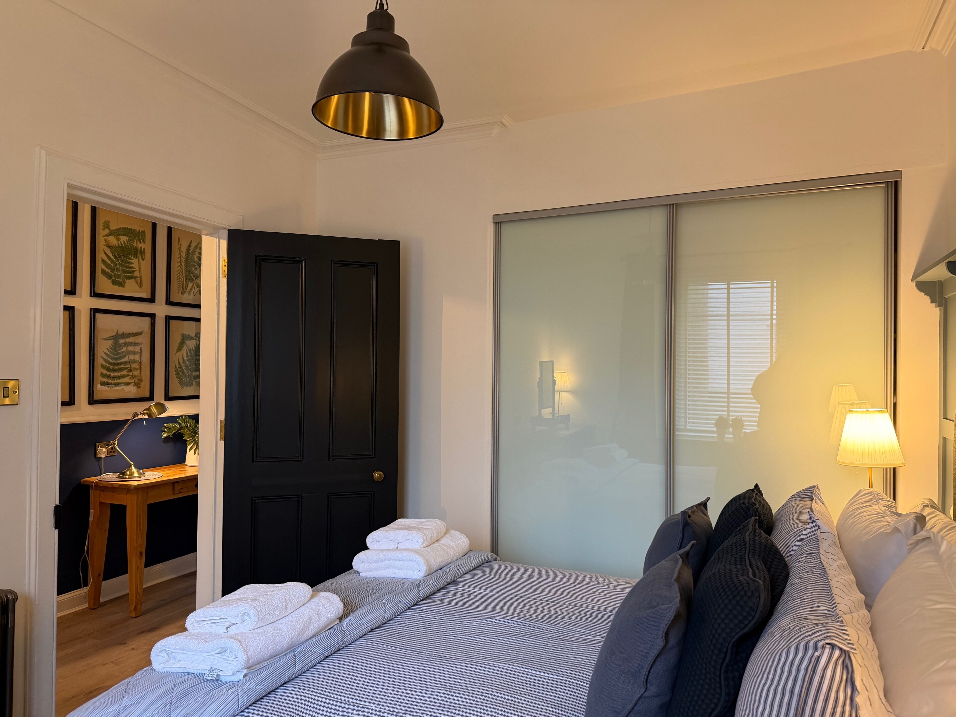 Ein Schlafzimmer mit einem Bett, einem Schreibtisch, einem Stuhl, einer Lampe und einem Kleiderschrank.