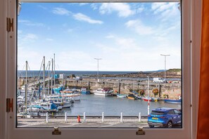 A marina with boats docked, a car parked in front, and a clear sky. - Seaview Apartment - 2bed on Anstruther Harbour (Anstruther)