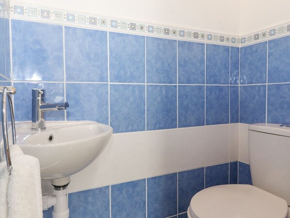 A bathroom with blue tiles, a white sink, and a toilet. - Wansfell View (Ambleside)