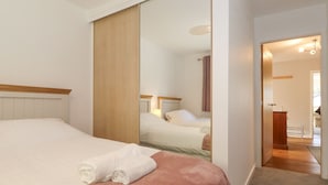 A hotel room with a bed, a large mirror, and a view of the bathroom. - Wansfell View (Ambleside)