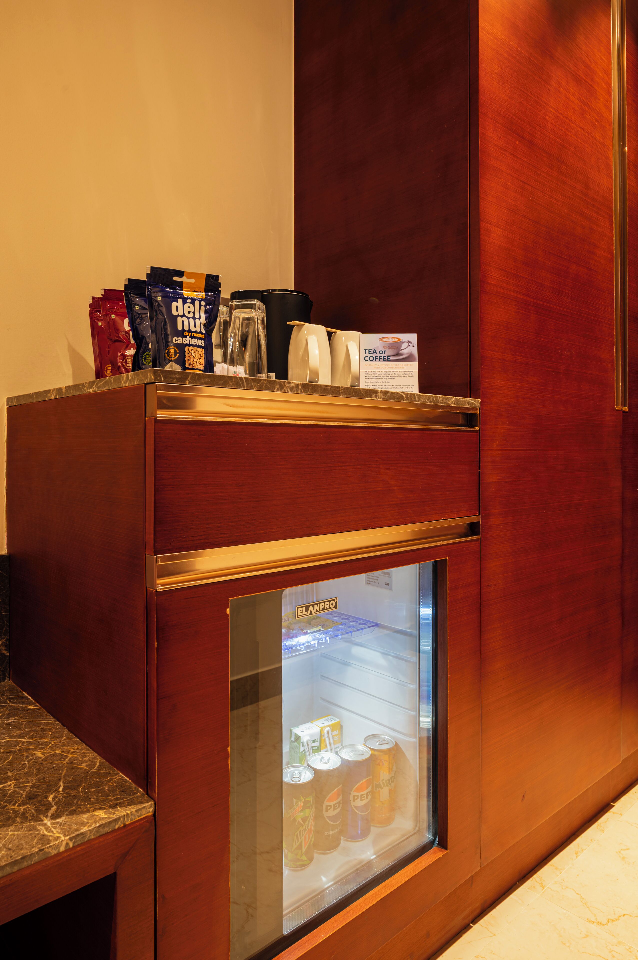 Un mini-bar contenant des en-cas, une machine à café et un réfrigérateur rempli de boissons.
