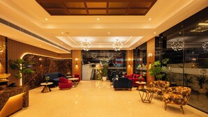 A modern lobby with a marble reception desk, plush seating, and a glass wall offering a view of the interior. - Hotel Classic Pavilion (Thiruvananthapuram)