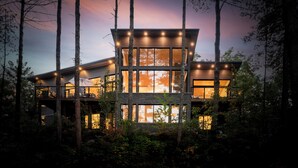 A modern multi-level cabin with large windows, surrounded by trees. - Top Rated Muskoka - Sauna • Fireplace • Chef Kitchen (Gravenhurst)