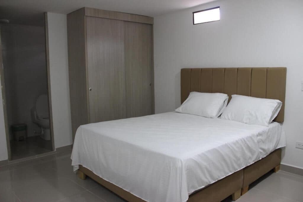A bedroom with a bed, a wardrobe, and a small stool.