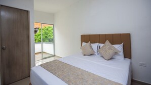 Una camera da letto con un letto grande, una porta in legno e vista sul verde.