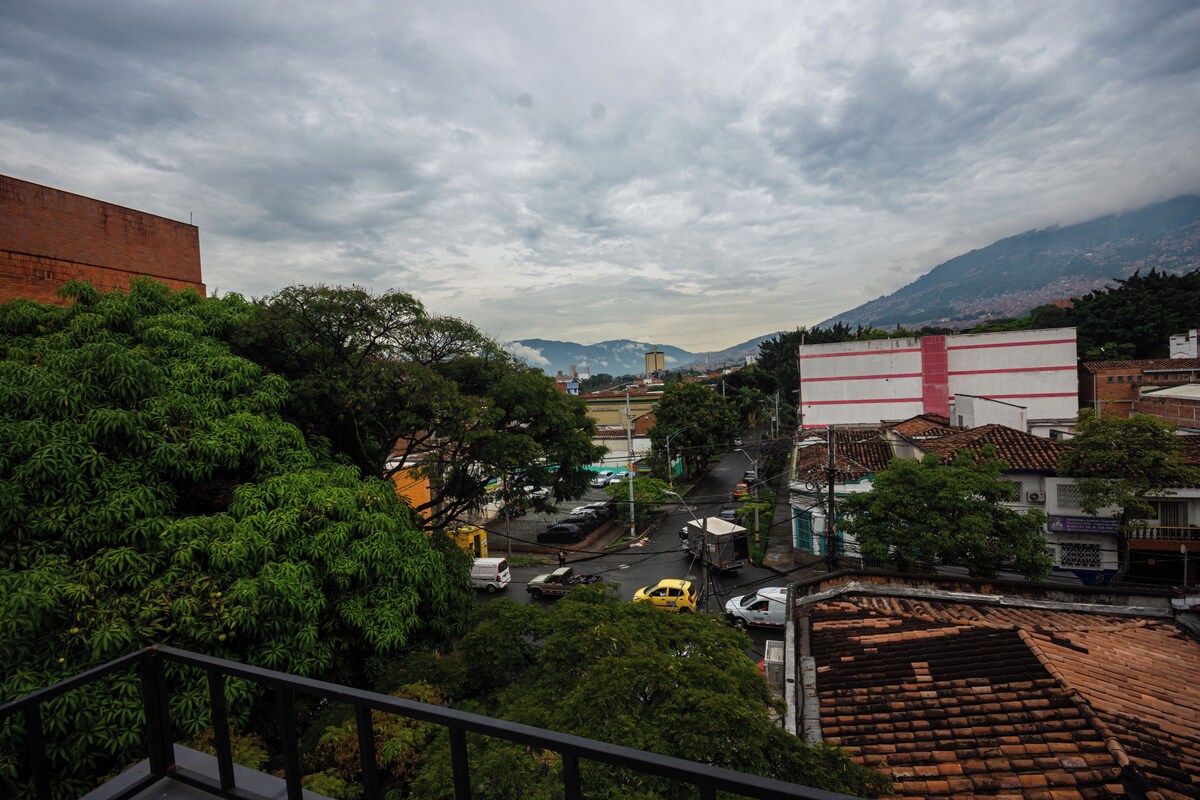 A cityscape with a prominent red building, a busy street with vehicles, and lush green trees.