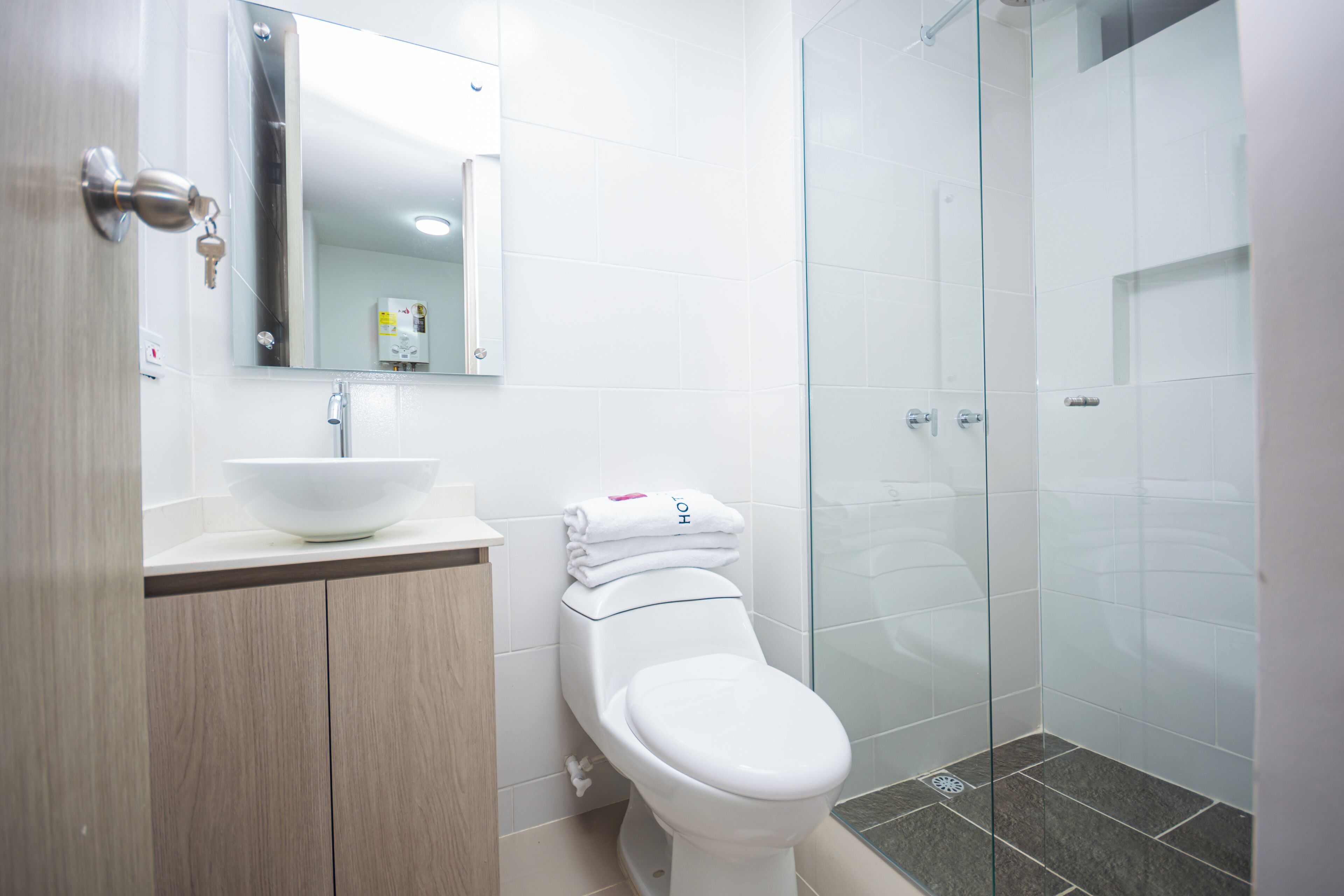 A modern bathroom with a white sink, toilet, and glass shower enclosure.