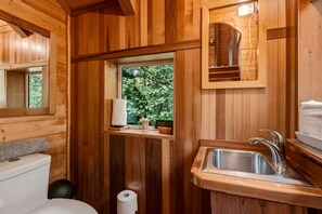 Een houten badkamer met toilet, wastafel en raam.