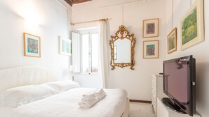 Quarto de hotel com uma cama grande, televisão e obras de arte nas paredes.