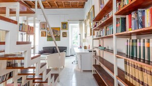 Uma biblioteca com estantes, uma mesa e uma escada.