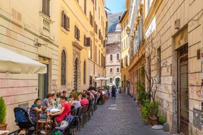 Eine enge Kopfsteinpflasterstraße gesäumt von Gebäuden, mit Außenbereich für Cafés.
