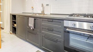 Cozinha moderna com armários escuros, forno de aço inoxidável e bancada de granito.