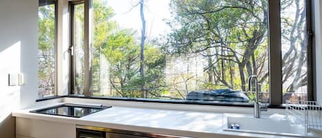 A kitchen with a large window, stainless steel appliances, and a dish rack.