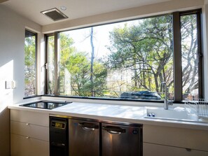 A kitchen with a large window, stainless steel appliances, and a dish rack. - A designer villa "floating" in the woods of Izu Kogen, designed by an architect to engage all five senses (accommodates up to 5 guests) (伊東市八幡野)