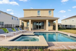 A two-story house with a swimming pool, outdoor seating, and a fenced backyard. - 4BR house with pool table near Disney (Kissimmee)
