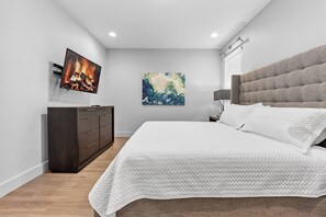 A bedroom with a bed, a dresser, a painting, and a TV displaying a fireplace. - 4BR house with pool table near Disney (Kissimmee)