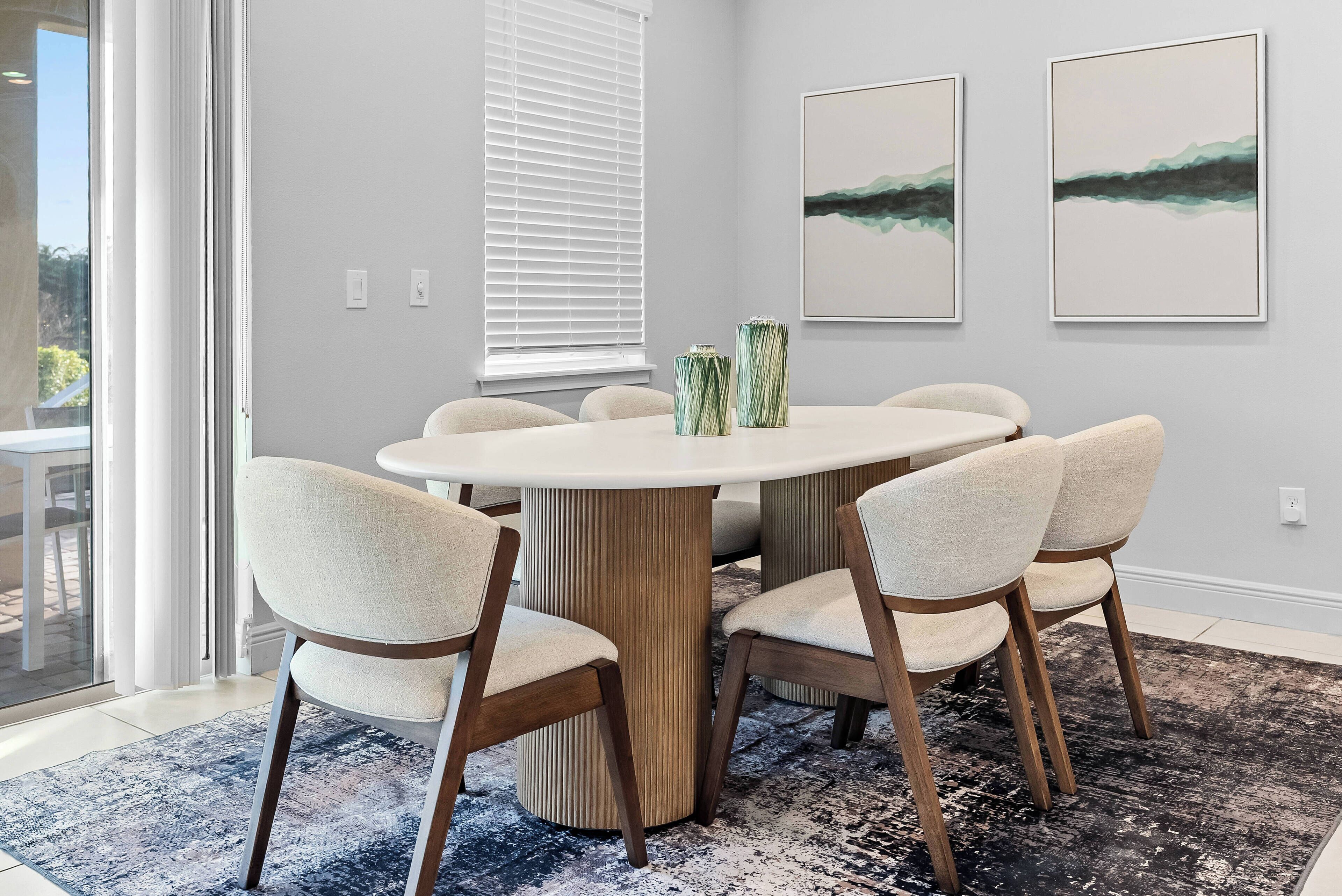 Un coin repas comprenant une table ronde, six chaises et deux vases.