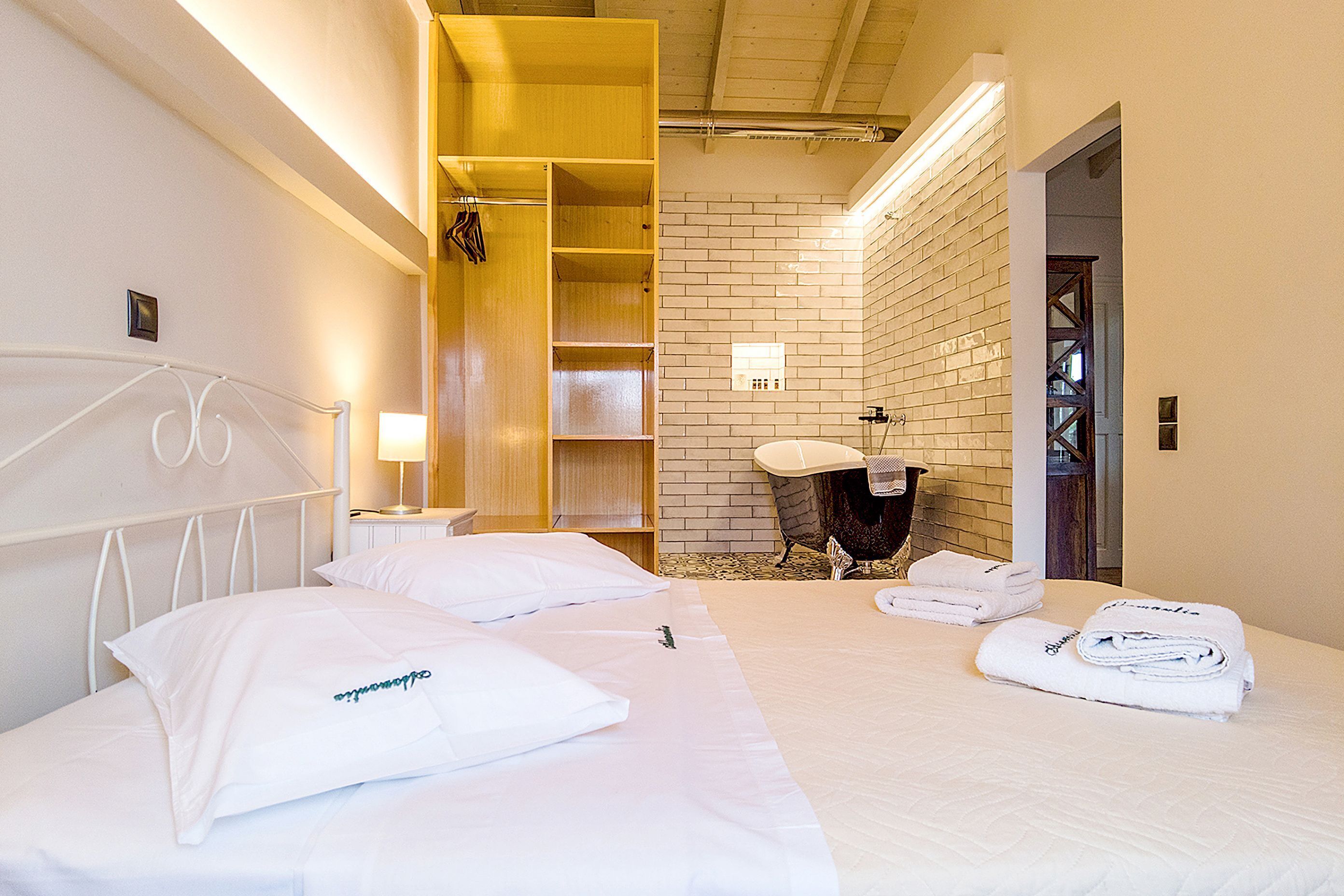 Habitació d'hotel amb llit, armari de fusta, bany amb mànega i mirall.